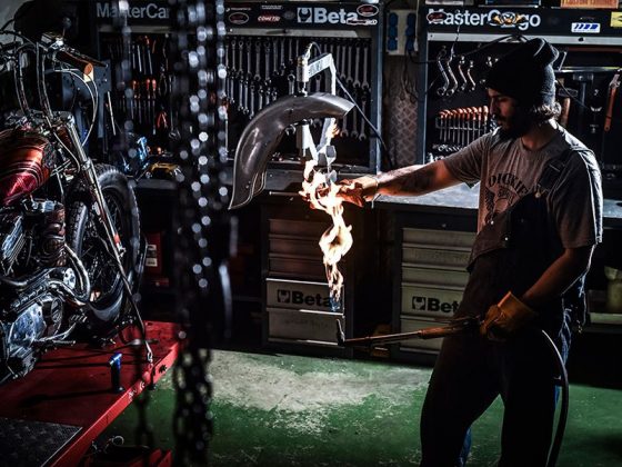 Trabajador de la empresa Inspiración Metálica Motor Company manipulando una pieza de metal con un soplete